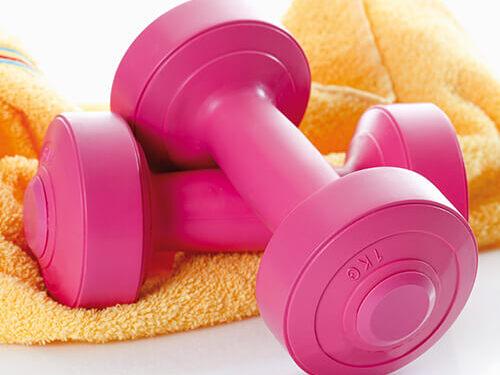 Zwei rosa Hanteln liegen auf einem gelben Handtuch.