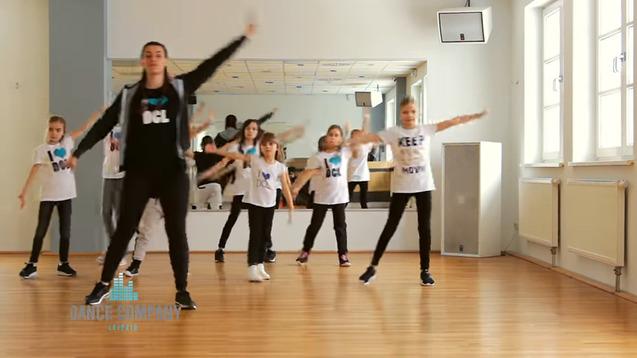 Gruppe von Kindern in Tanzkleidung, die einen Tanzunterricht in einem Studio mit Spiegeln absolvieren.
