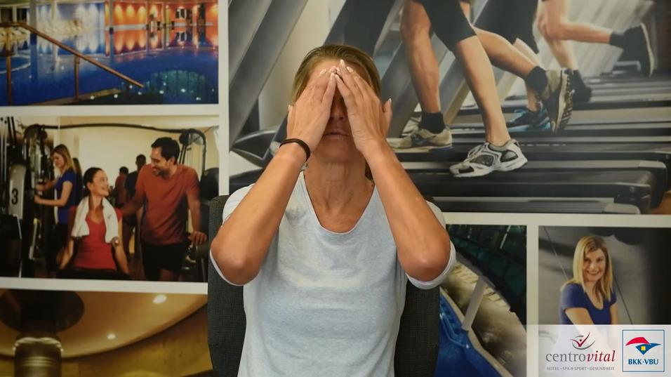 Frau mit geschlossenen Augen und Händen im Gesicht vor einem Sportmotiv-Hintergrund.