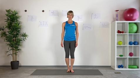 Frau in Sportbekleidung steht auf einer Yogamatte vor einer Wand mit Übungsanleitungen und Fitnessgeräten.