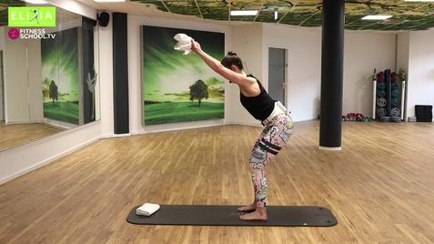 Frau in Sportkleidung führt eine Übung auf einer Matte in einem Fitnessstudio mit Spiegeln und grünen Wänden aus.