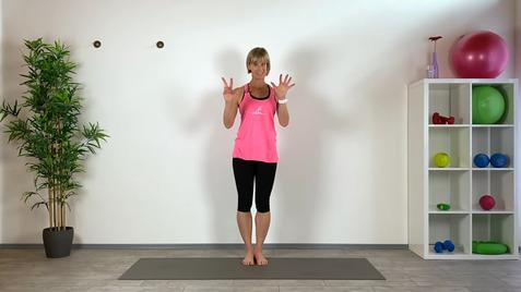 Frau in pinkem Sporttop steht auf einer Matte und zeigt beide Hände mit gespreizten Fingern vor einer Wand.