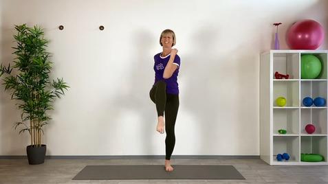 Frau in Sportkleidung hebt ein Bein und zeigt mit der Hand einen motivierenden Gestus in einem Fitnessraum.