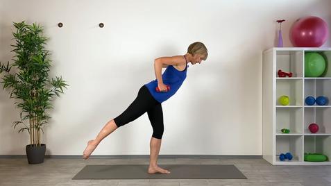 Frau in Sportkleidung führt eine Übung mit roten Hanteln auf einer Yogamatte in einem hellen Raum durch.