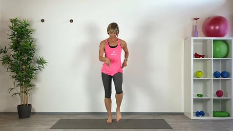 Eine Frau in einem pinken Top führt Übungen auf einer Yogamatte in einem hellen Raum mit Pflanzen und Fitnessgeräten aus.