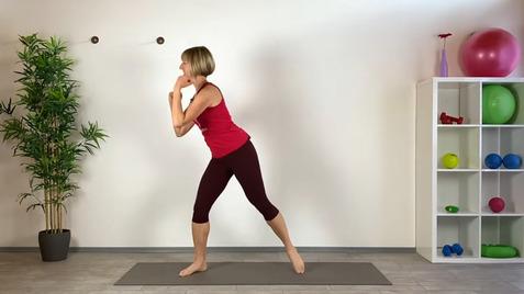 Frau in sportlicher Kleidung führt eine Übung auf einer Matte in einem Trainingsraum aus, umgeben von Fitnessgeräten.