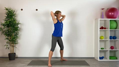 Frau in blauer Sportbekleidung führt eine Übung auf einer Yogamatte in einem hellen Raum mit Fitnessgeräten aus.