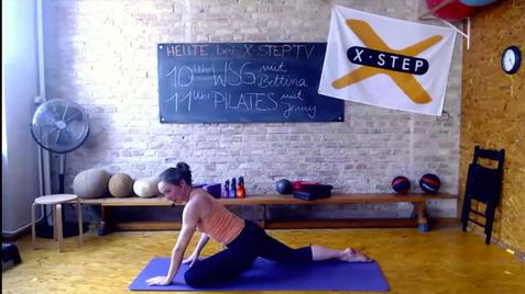 Frau in Yogapose auf einer Matte in einem Fitnessraum mit Trainingsgeräten und Tafel im Hintergrund.