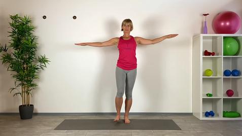 Frau in Sportkleidung mit ausgestreckten Armen auf einer Trainingsmatte, umgeben von Fitnessgeräten und Pflanzen.