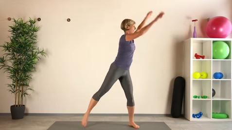 Frau in Sportkleidung führt einen Fitnesssprung auf einer Matte in einem hellen Raum durch.