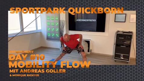 Mann in Trainingskleidung führt eine Mobilitätsübung in einem modernen Raum mit Bildschirm und Lautsprecher aus.