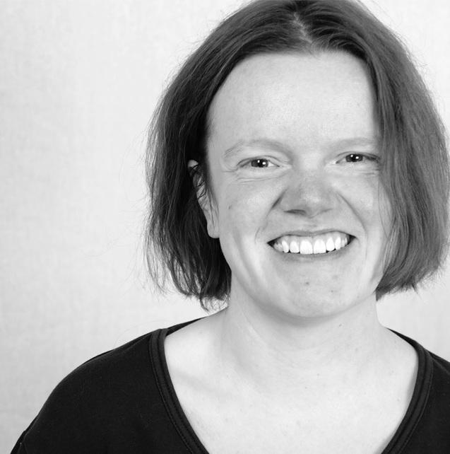 Porträt einer lächelnden Frau mit schulterlangen Haaren in einem schwarzen Oberteil vor neutralem Hintergrund.