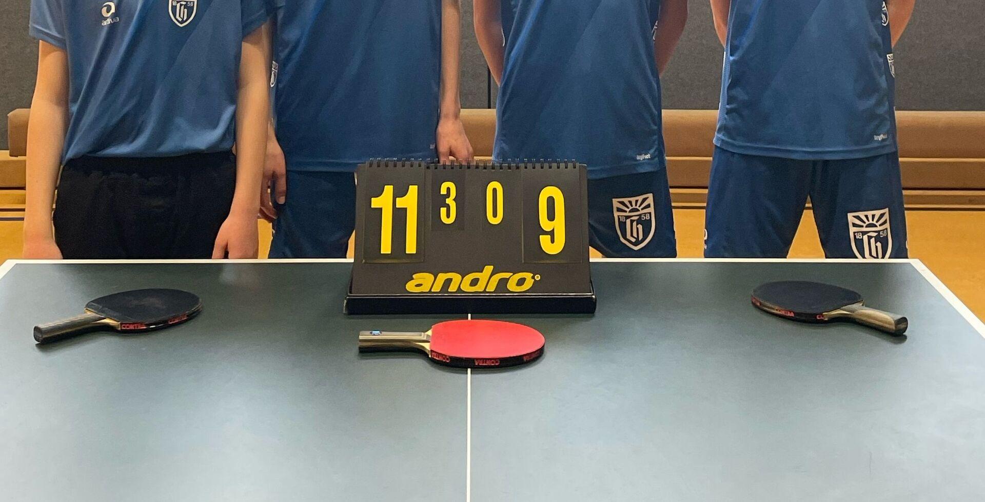 Gruppenfoto von vier jungen Menschen in Trikot hinter einer Tischtennisplatte
